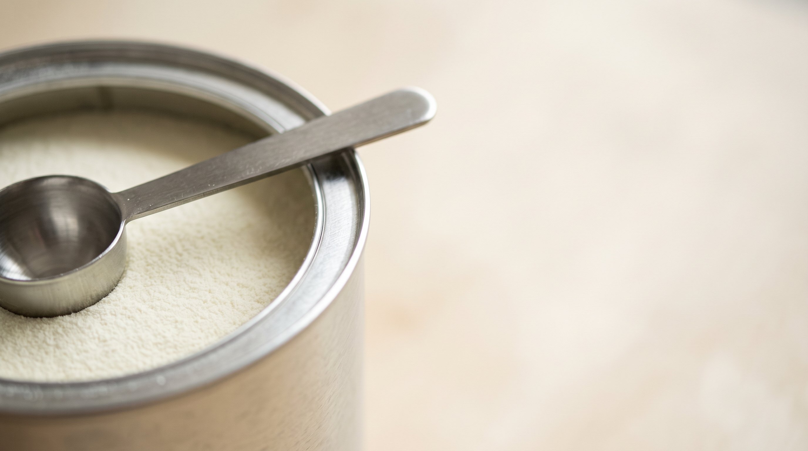Tin of milk powder with a stainless steel measuring scoop
